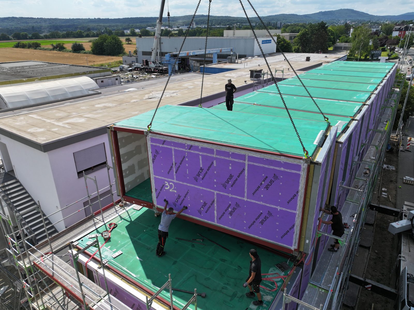 Ein Raummodul des Pacarada Modulbausystems wird per Kran auf das Gebäude in Liederbach am Taunus gesetzt